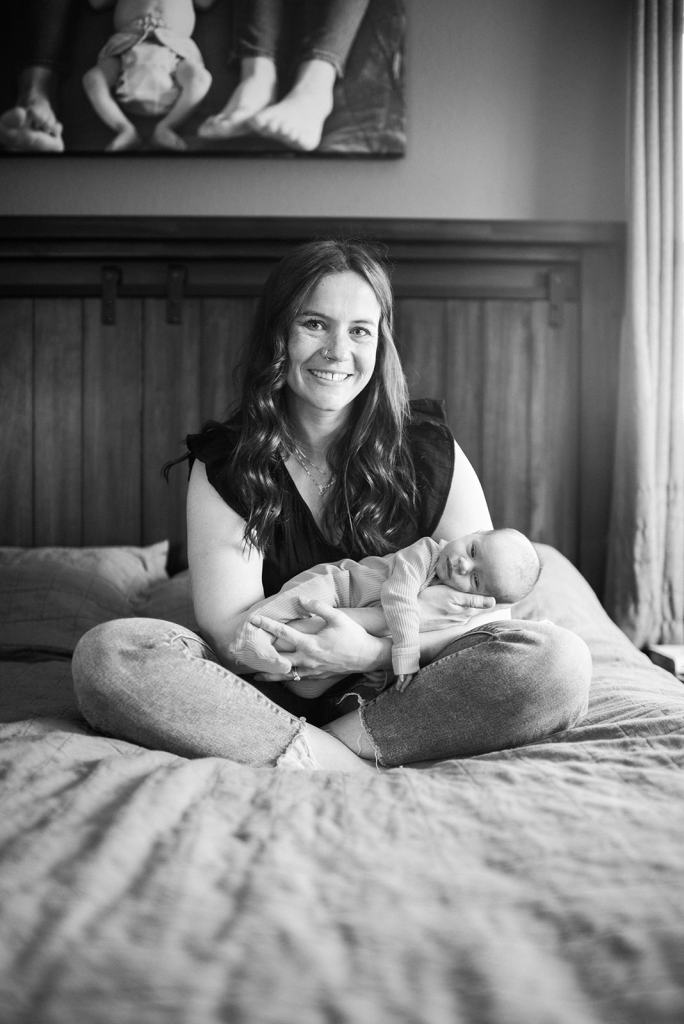Karli holding a baby while sitting on a bed